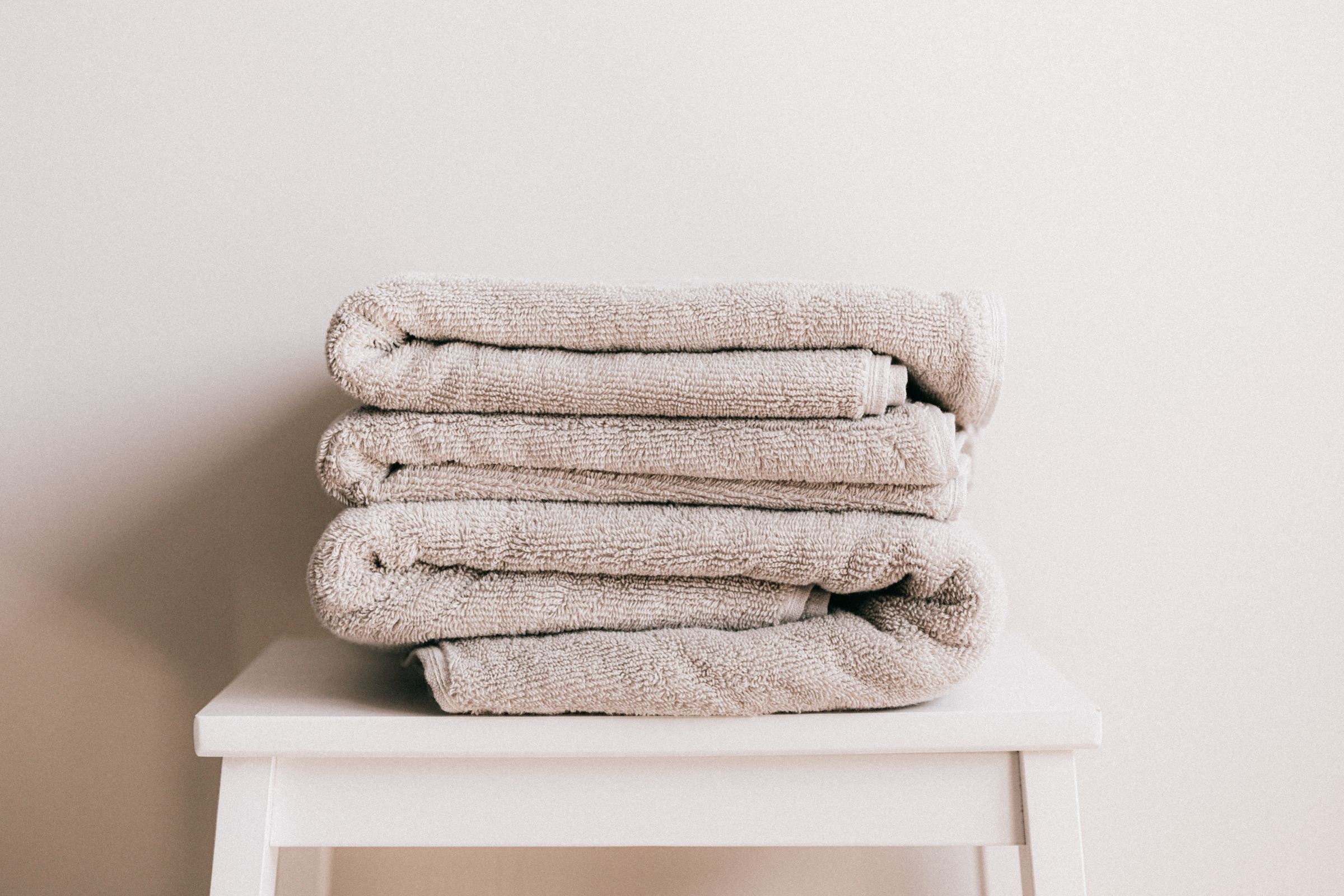 Professionally folded commercial bed and bath linens staged on a shelf, ready for hotel and healthcare delivery
